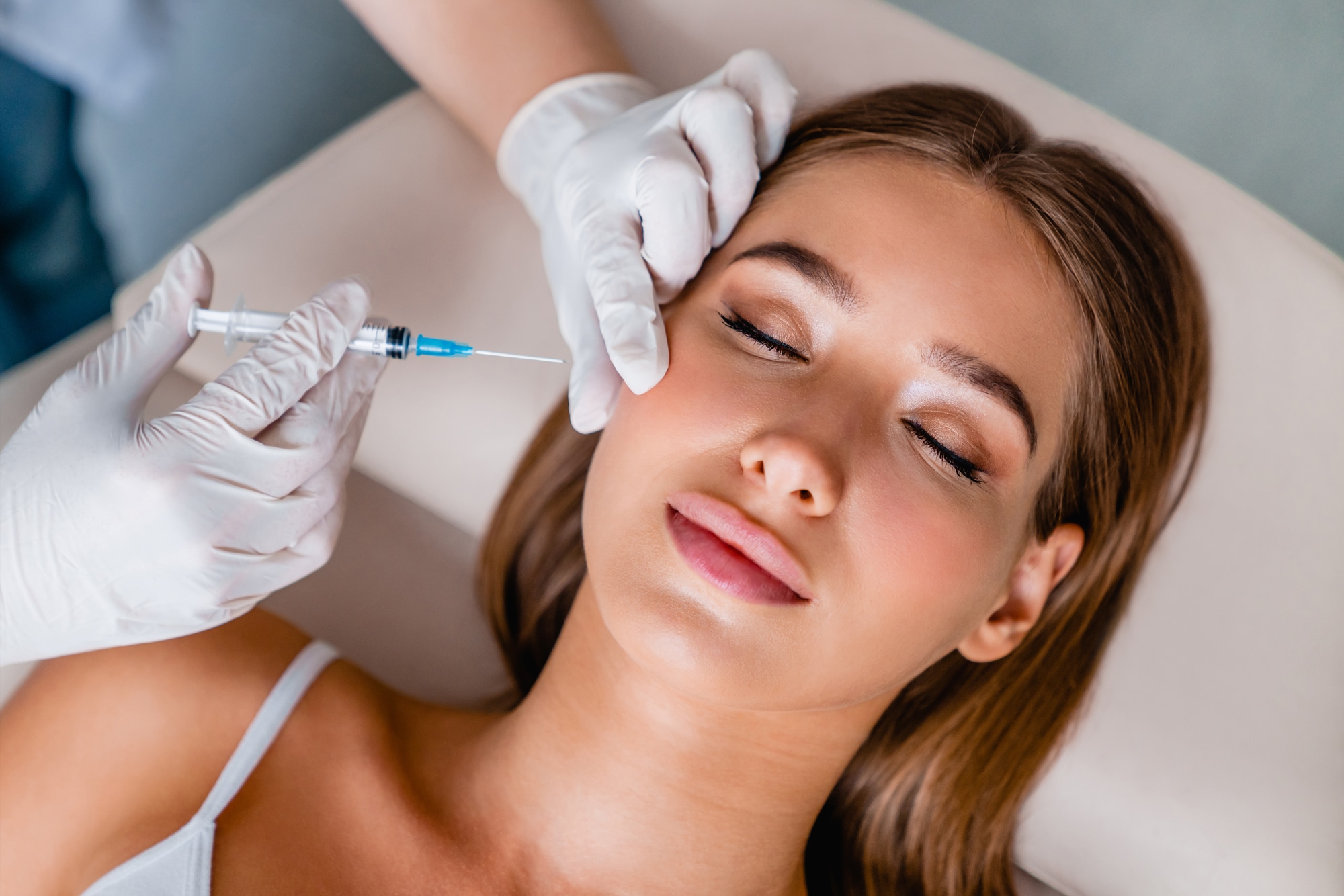 Young woman gets Botox facial injections in salon