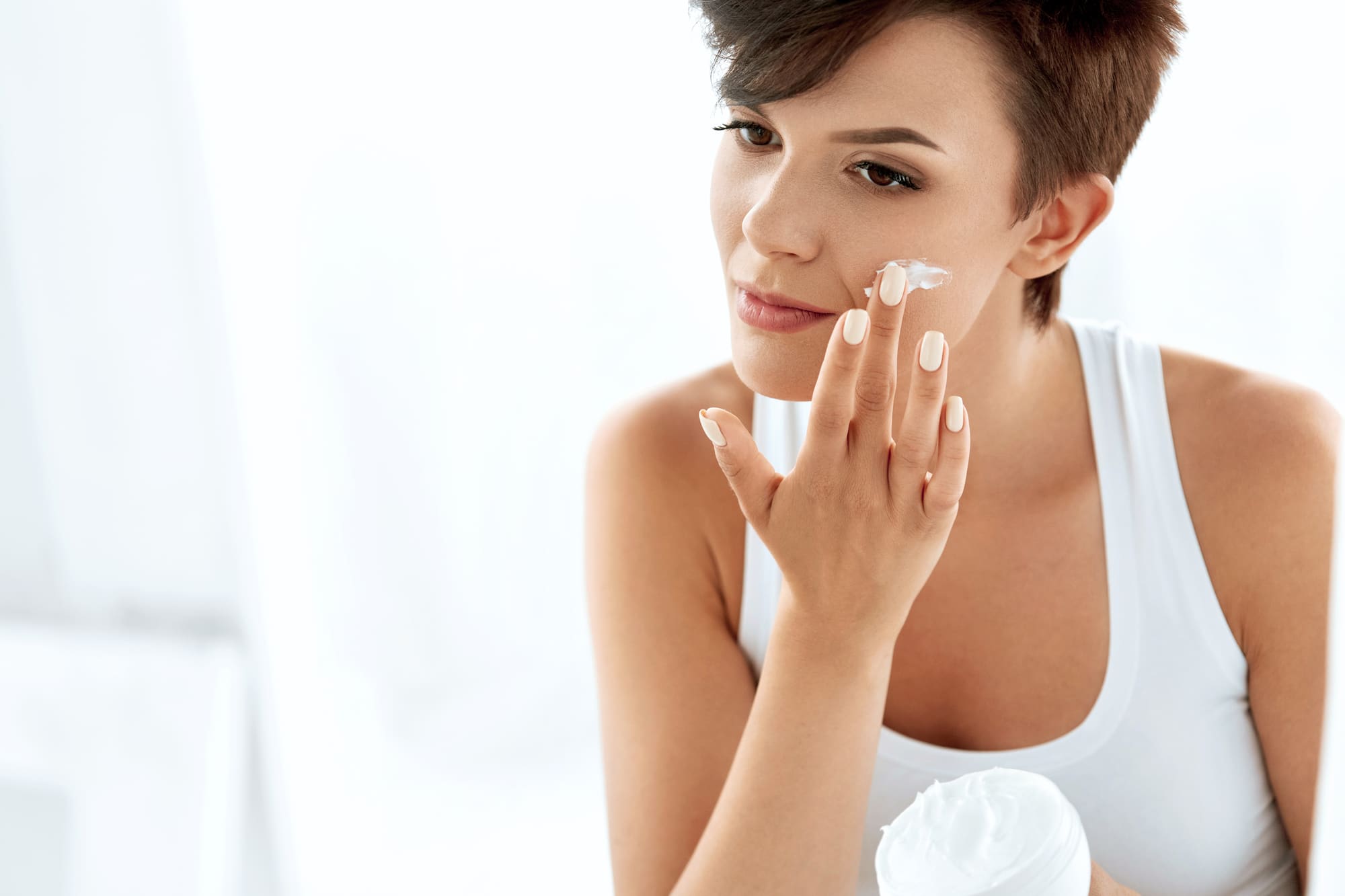 Beauty Skin Care. Beautiful Woman Applying Cosmetic Face Cream